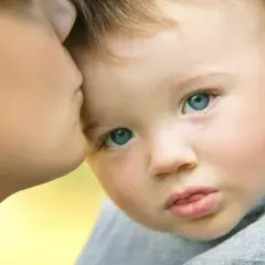 Un bambino con autismo e paura degli estranei piange mentre riceve un bacio rassicurante dalla madre.