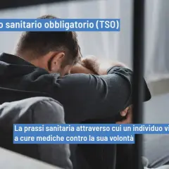 Uomo seduto, testa china, simbolo di un TSO (Trattamento Sanitario Obbligatorio). La prassi sanitaria che impone cure mediche.