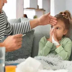 Padre controlla la febbre alla figlia, che soffia il naso, mostrando i tipici adenovirus sintomi.