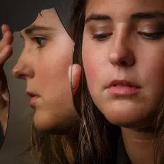 Ragazza con volto riflesso in uno specchio rotto, un'immagine che evoca cosa fa arrabbiare un bipolare.