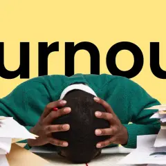 Persona con la testa tra le mani, circondata da pile di documenti, con la parola "Burnout" in grande sullo sfondo giallo. Sintomi di esaurimento.