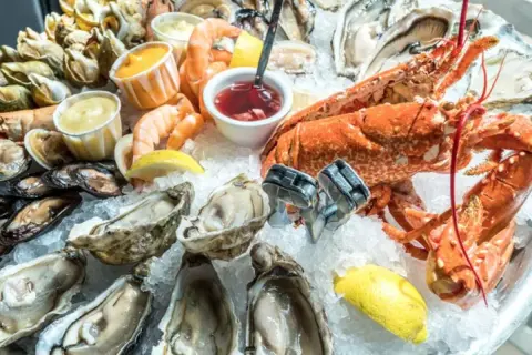 Un vassoio di frutti di mare su ghiaccio, con ostriche, gamberi, aragosta e cozze. Potrebbe scatenare la paura irrazionale di crostacei e molluschi in qualcuno.