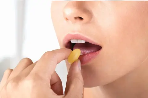 Donna assume levofloxacina 500 mg, una capsula gialla viene inserita nella bocca aperta.