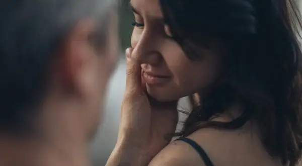 Una mano sfiora il viso di una donna, un gesto che rivela il profondo significato psicologico di una carezza: conforto, amore e connessione.