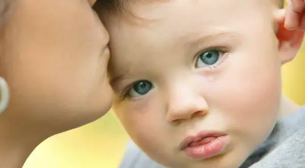 Un bambino con autismo e paura degli estranei piange mentre riceve un bacio rassicurante dalla madre.
