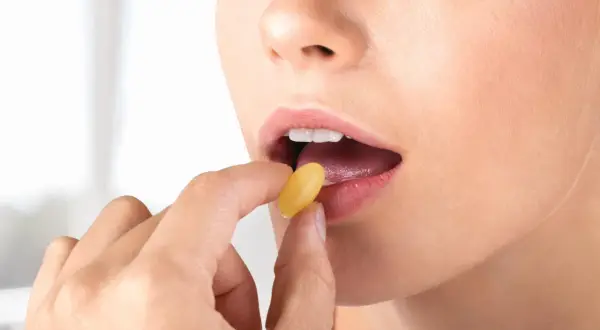 Donna assume levofloxacina 500 mg, una capsula gialla viene inserita nella bocca aperta.