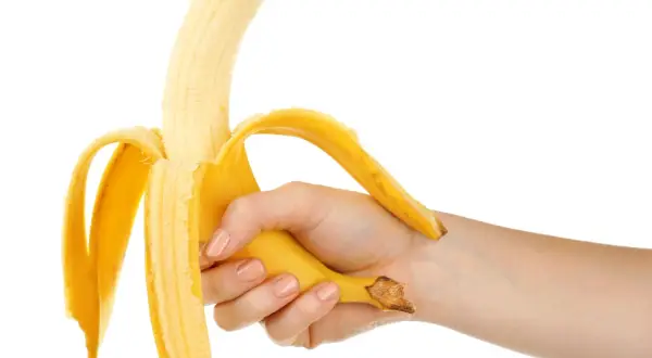 Mano che sbuccia una banana, simbolo di forza e vitalità, in contrasto con la disfunzione erettile.