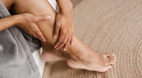 Mani che massaggiano un polpaccio, forse per alleviare il dolore da acido lattico dopo un allenamento intenso.