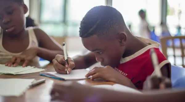 Bambini concentrati sui loro quaderni, alcuni con DSA e ADHD, imparano e scrivono con impegno.