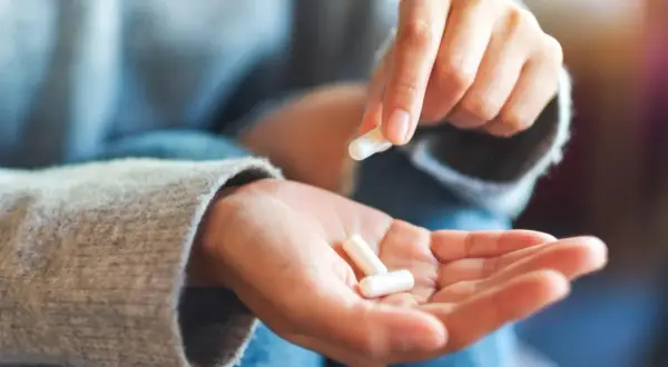 Mano che tiene capsule bianche, per capire diflucan a cosa serve.
