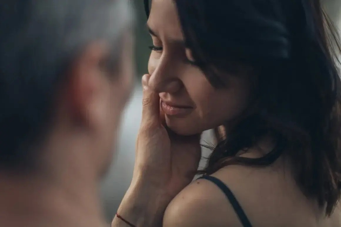 Una mano sfiora il viso di una donna, un gesto che rivela il profondo significato psicologico di una carezza: conforto, amore e connessione.