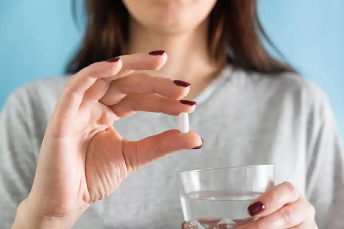 Donna tiene una pillola bianca, forse per il colesterolo, e un bicchiere d'acqua. Torvast a cosa serve?