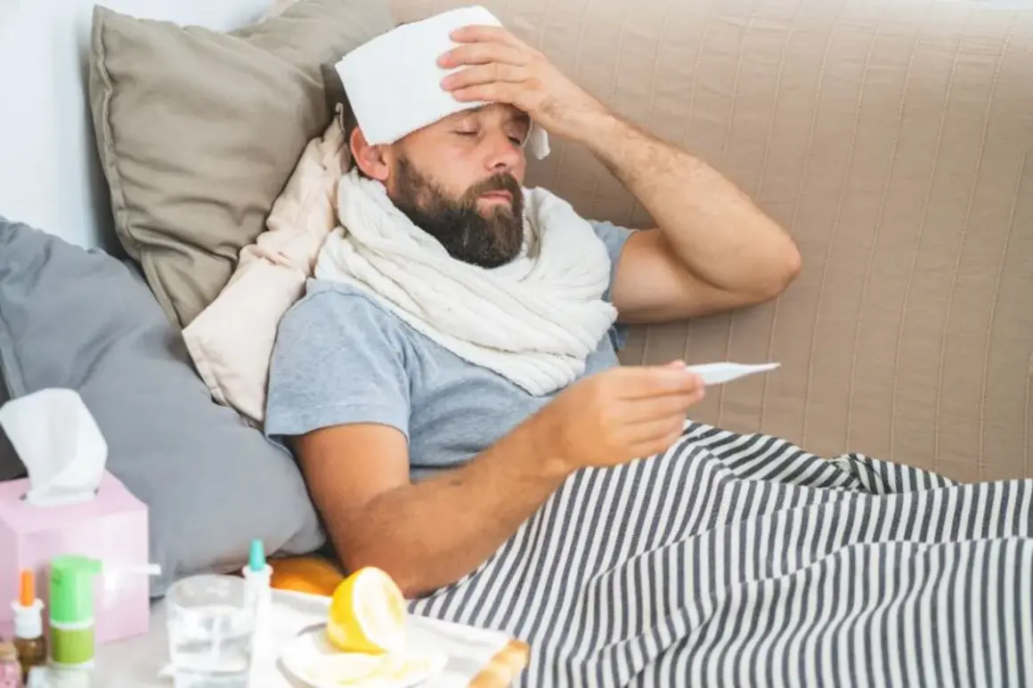 Uomo a letto con termometro e panno umido sulla fronte, cerca consigli su come abbassare la febbre. Sul comodino, limone e bicchiere d'acqua.