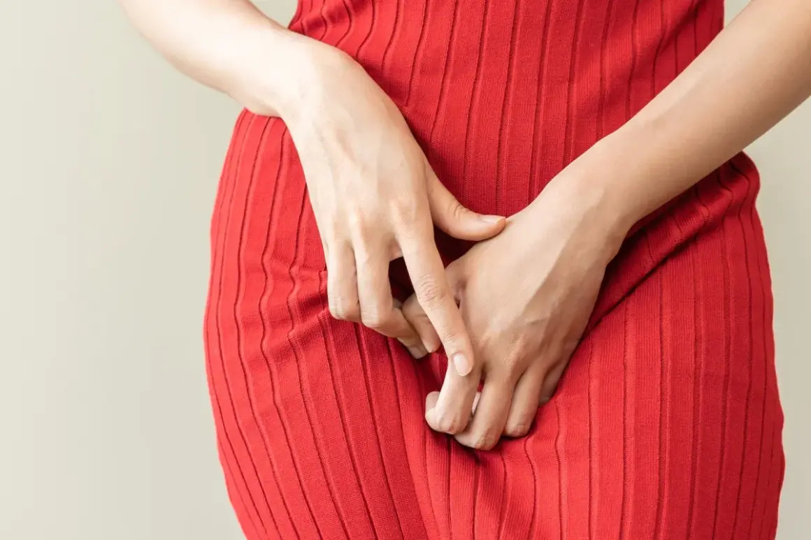 Mani che si stringono sul vestito rosso, un gesto che può indicare disagio, forse legato alla candida o al ciclo mestruale.