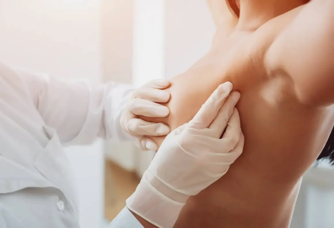 Mani guantate di un medico esaminano un seno, un'immagine che ricorda l'importanza di riconoscere i sintomi del tumore al seno.