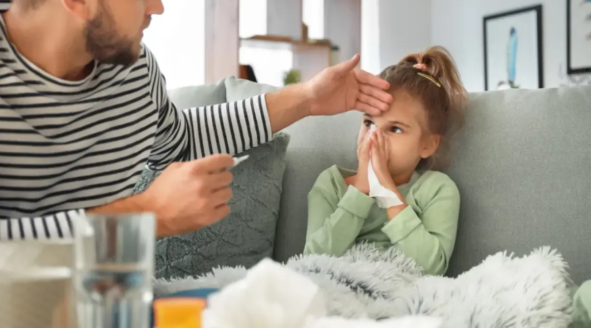 Padre controlla la febbre alla figlia, che soffia il naso, mostrando i tipici adenovirus sintomi.