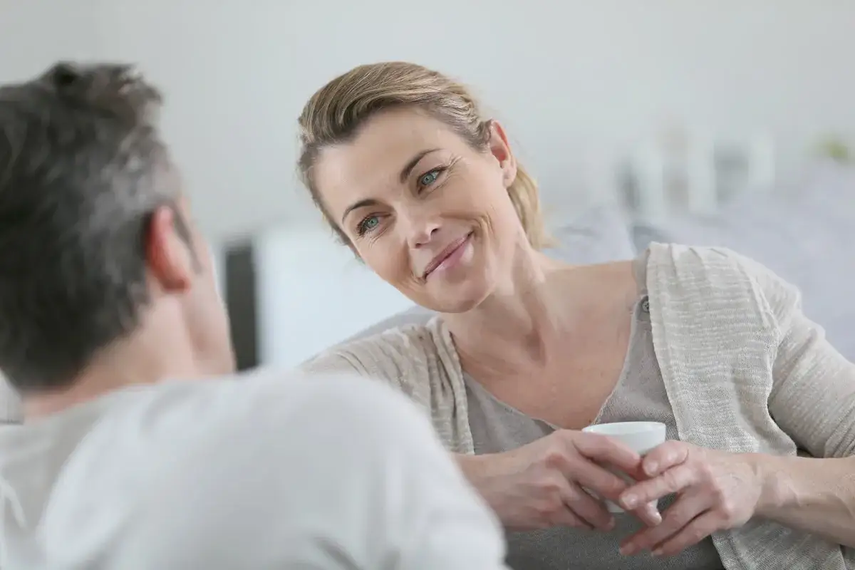 Donna con sguardo intenso e sorriso accennato, forse un'espressione di attaccamento ansioso ambivalente, mentre tiene una tazza.