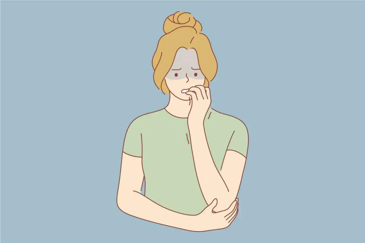 Ragazza ansiosa si morde le unghie, manifestando labbra secche cause psicologiche.