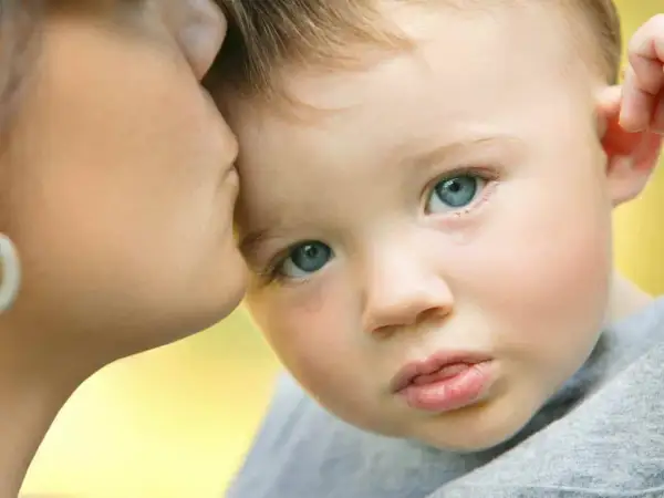 Un bambino con autismo e paura degli estranei piange mentre riceve un bacio rassicurante dalla madre.