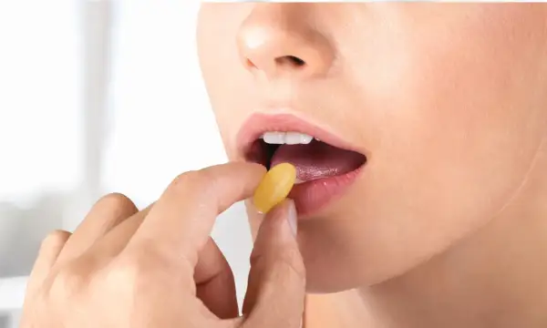 Donna assume levofloxacina 500 mg, una capsula gialla viene inserita nella bocca aperta.