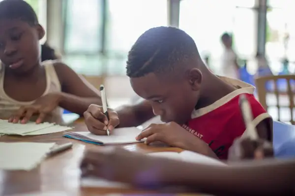 Bambini concentrati sui loro quaderni, alcuni con DSA e ADHD, imparano e scrivono con impegno.